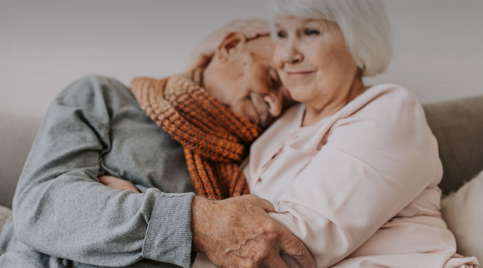 Elderly woman embracing elderly man